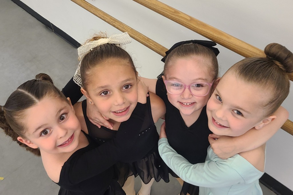 four young dancers hugging